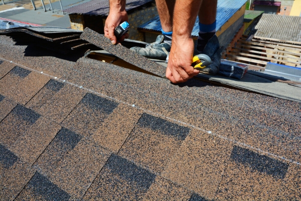 A TAG Roofing & Exteriors crew member laying out shingles on the edge of a roof.