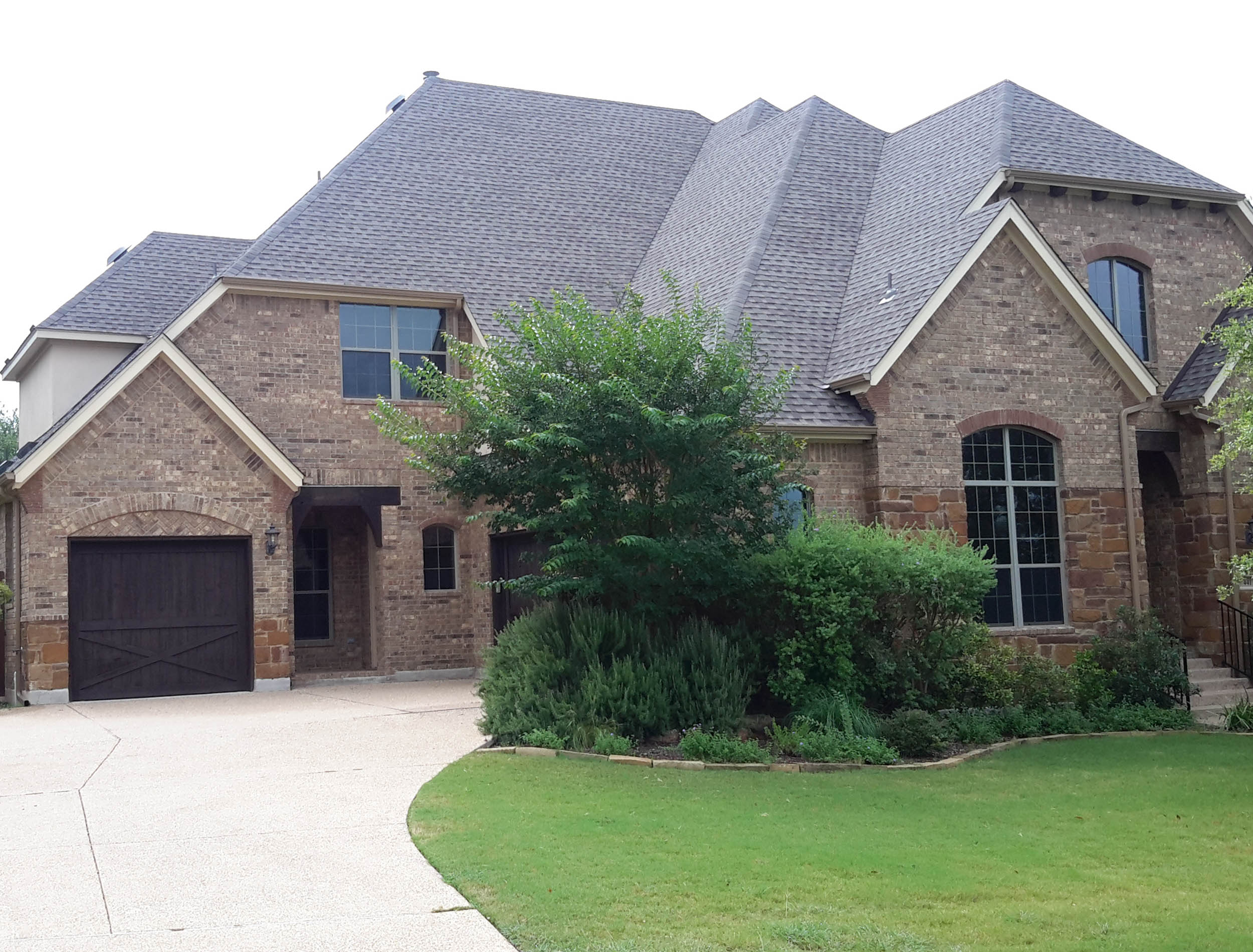 A beautiful brick home with new shingles installed by TAG Roofing & Exteriors
